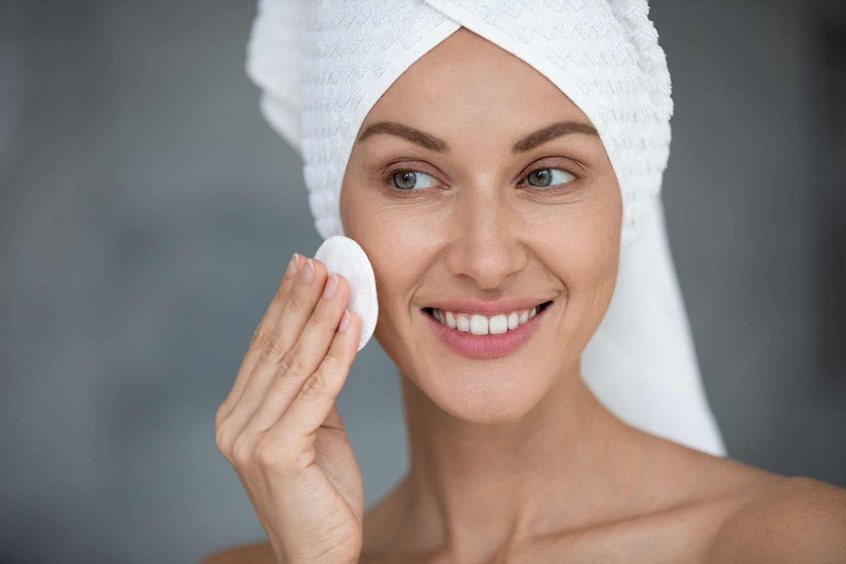 Woman cleans face skin removing makeup uses cotton pad 